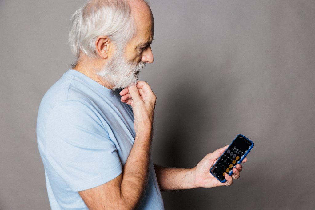 senior en réflexion sur un calcul sur son téléphone