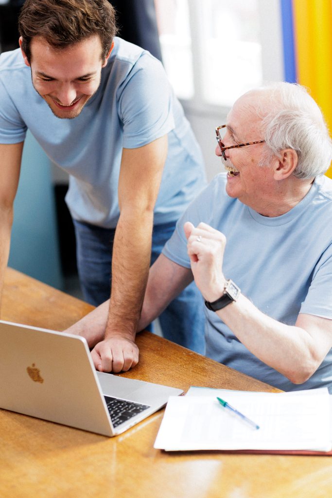 senior devant son ordinateur en train de s'amuser avec son petit fils