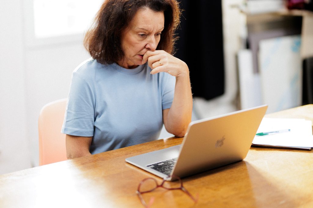 femme âgée réfléchissant devant son ordinateur