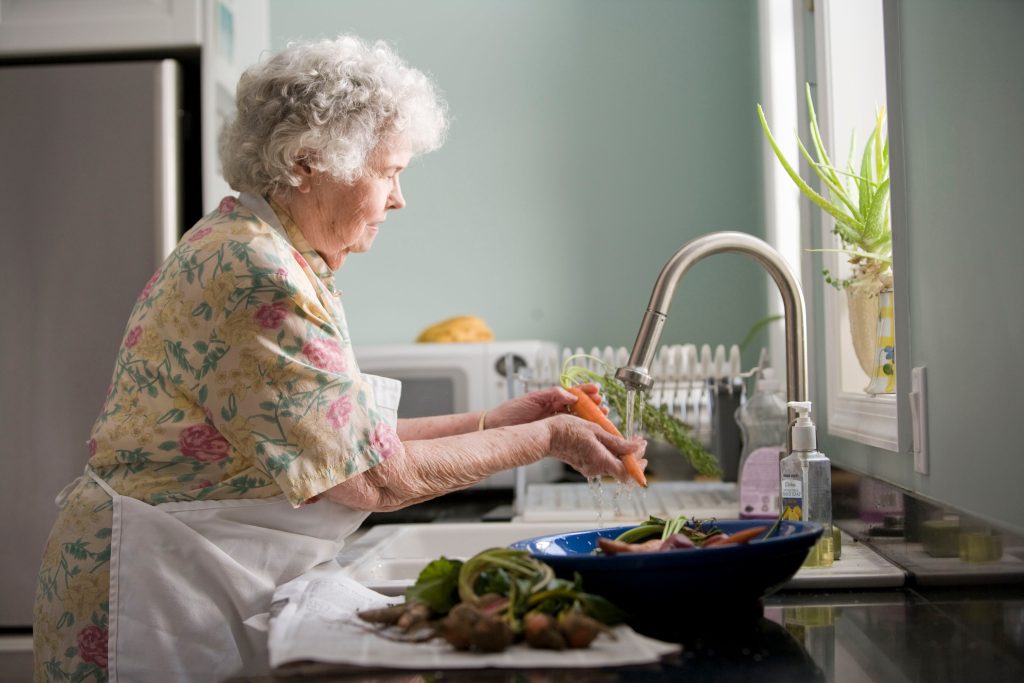 dame âgée en train de laver des légumes pour cuisiner