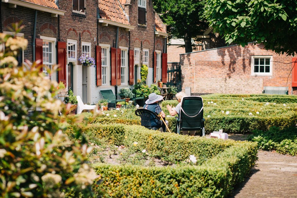 couple de seniors assis devant leur maison